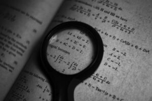 monochrome photo of math formulas and magnifying glass
